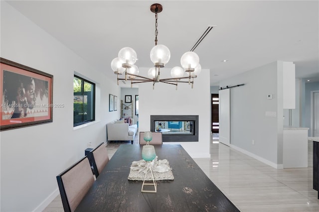 dining room featuring a barn door, a multi sided fireplace, and a chandelier