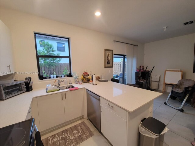 kitchen featuring white cabinets, light tile patterned flooring, kitchen peninsula, stainless steel dishwasher, and range