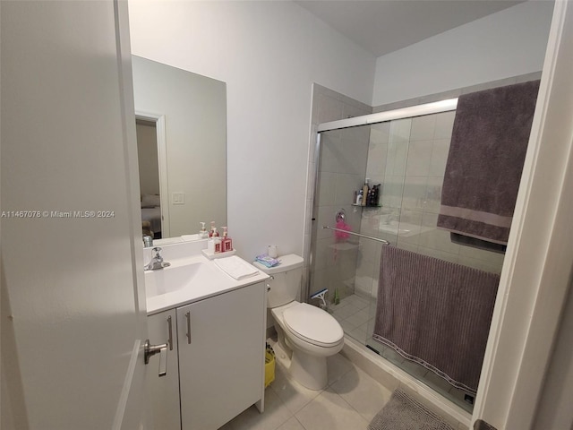 bathroom with tile patterned flooring, a shower with door, vanity, and toilet