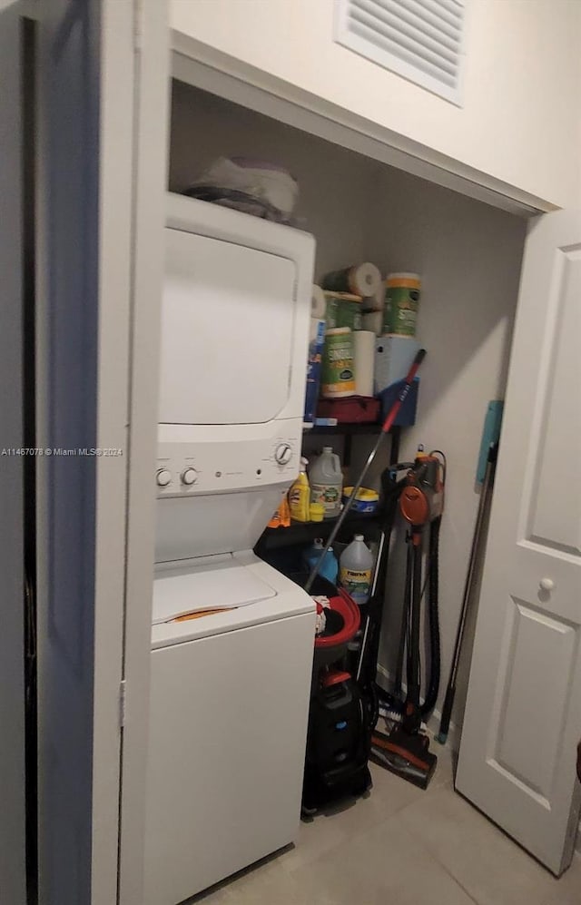 laundry room featuring light tile patterned floors and stacked washing maching and dryer