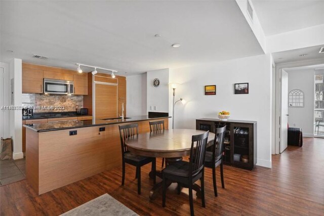 dining area featuring track lighting, dark wood-type flooring, and sink