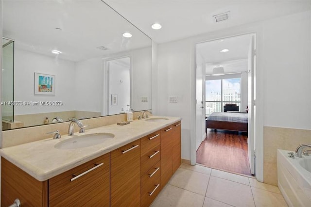 bathroom featuring vanity with extensive cabinet space, tile flooring, double sink, and a bathtub