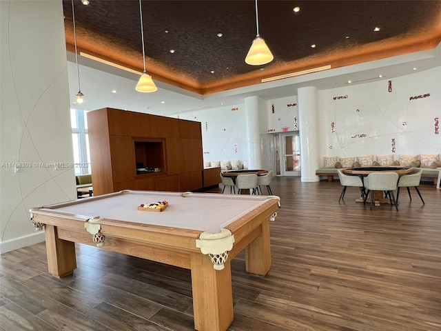 recreation room with a tray ceiling, billiards, and dark wood-type flooring