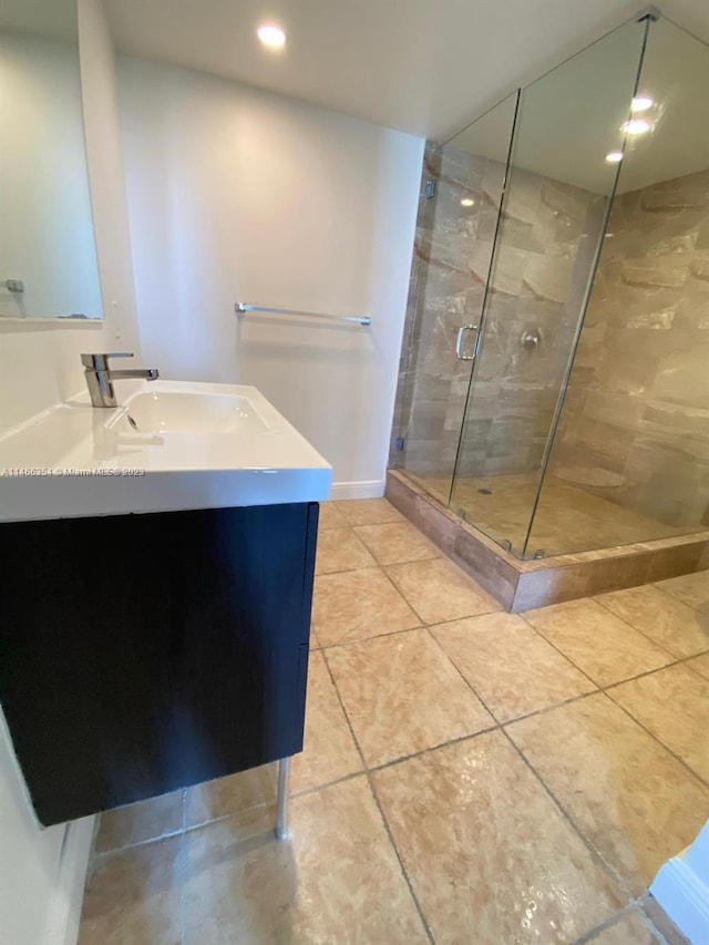 bathroom with vanity, tile floors, and a shower with door