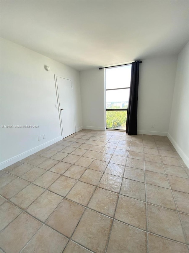 tiled empty room featuring floor to ceiling windows