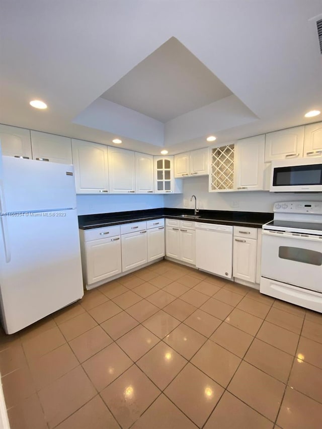 kitchen featuring white appliances, white cabinetry, a tray ceiling, and sink