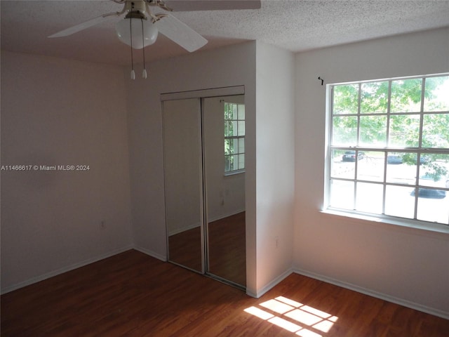 unfurnished bedroom featuring a closet, a textured ceiling, dark hardwood / wood-style floors, and ceiling fan