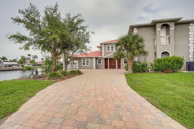 mediterranean / spanish house featuring a front yard, a water view, and central AC