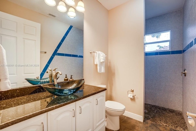 bathroom with tiled shower, vanity, and toilet