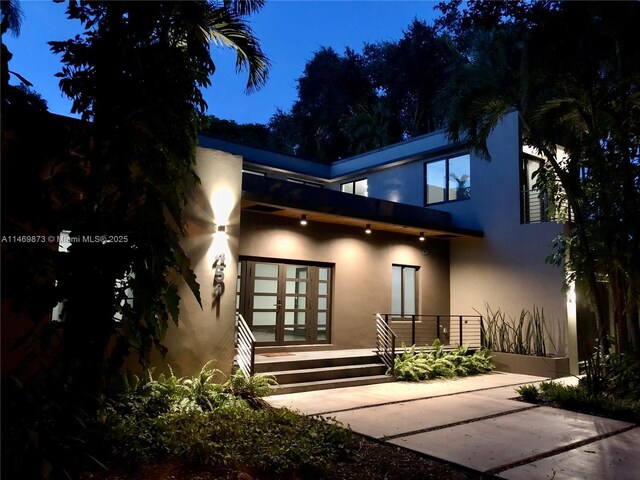 view of front of house with a balcony, a garage, and french doors