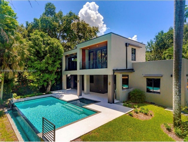 rear view of property with a lawn, a balcony, and a patio area