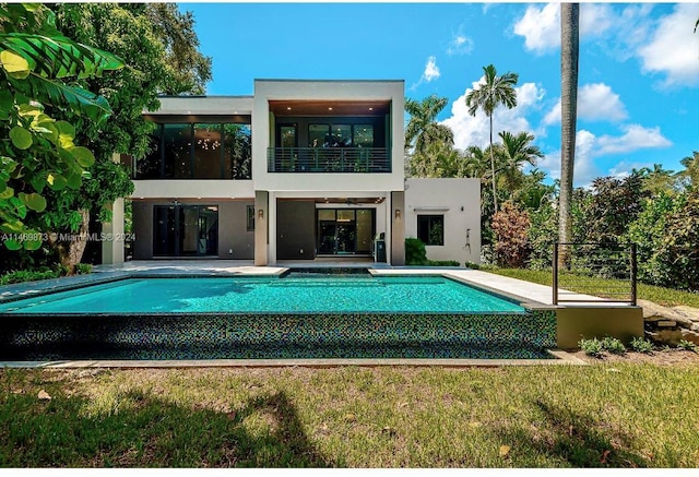 rear view of house featuring a patio, a balcony, and a lawn