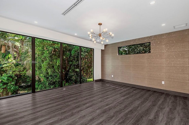 spare room featuring dark wood-type flooring and a chandelier