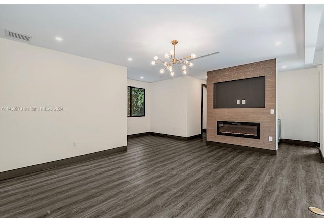 unfurnished living room with dark hardwood / wood-style floors, a fireplace, and a chandelier