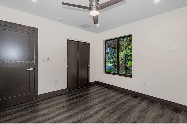 unfurnished bedroom featuring dark wood-type flooring, ceiling fan, and a closet