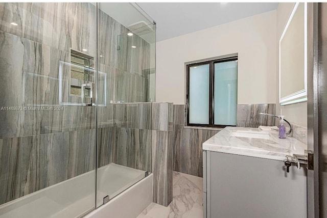 bathroom featuring tile walls, vanity, and tiled shower / bath combo