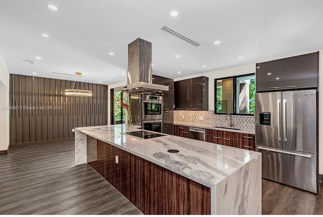 kitchen featuring sink, light stone counters, island range hood, a center island, and stainless steel appliances