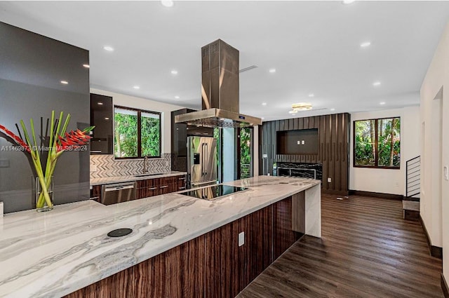 kitchen featuring tasteful backsplash, island range hood, dark hardwood / wood-style floors, stainless steel appliances, and light stone countertops