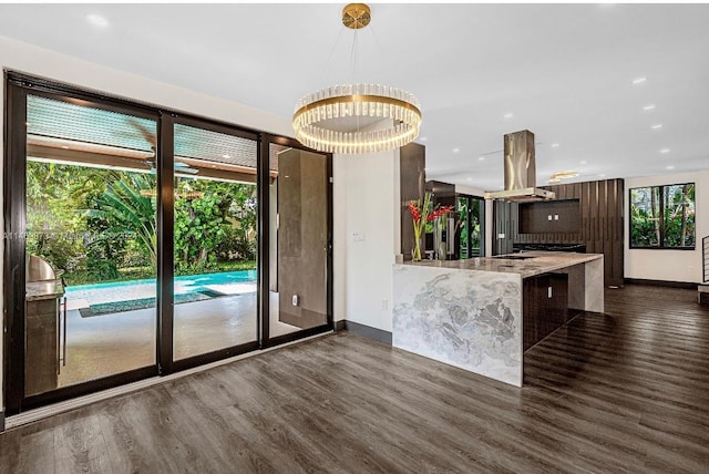 kitchen with dark hardwood / wood-style flooring, a kitchen bar, kitchen peninsula, and island exhaust hood