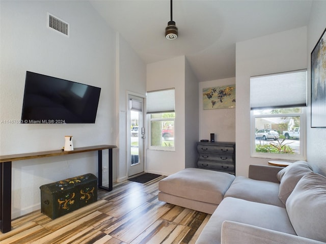 living room featuring lofted ceiling, light hardwood / wood-style floors, and plenty of natural light