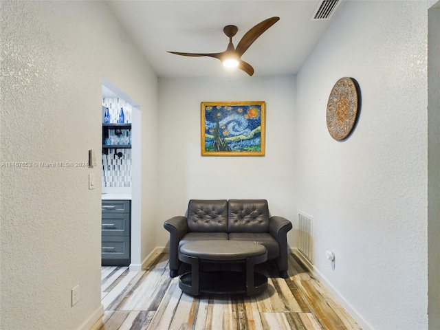 living area with light hardwood / wood-style floors and ceiling fan