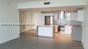 kitchen featuring white cabinets, appliances with stainless steel finishes, wall chimney exhaust hood, and a center island