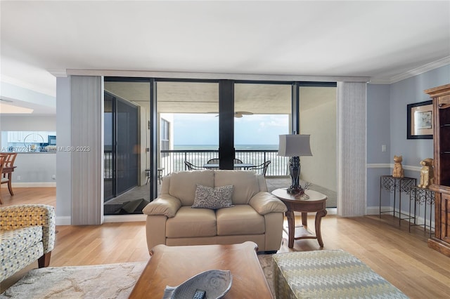 living room with a wall of windows, a water view, light wood-type flooring, and crown molding