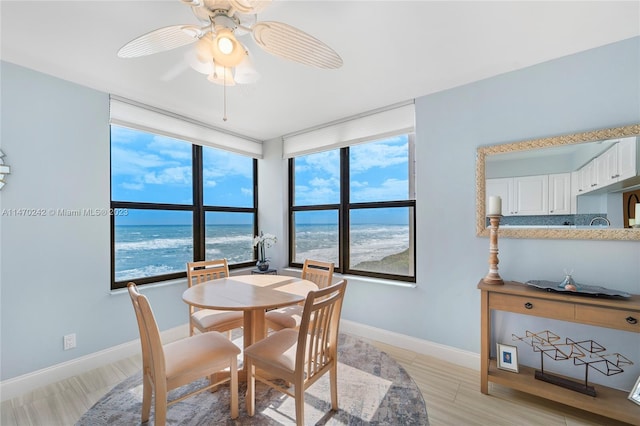 dining room featuring light hardwood / wood-style floors, ceiling fan, and a water view