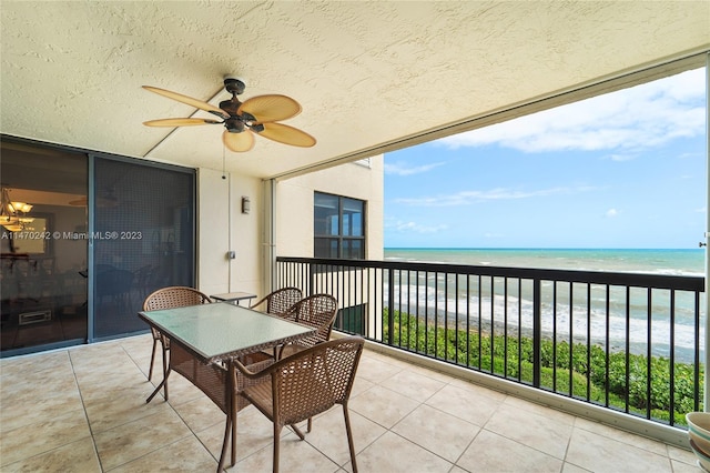 balcony with a view of the beach, a water view, and ceiling fan