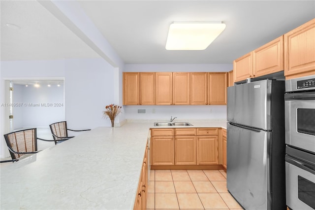 kitchen featuring light tile floors, appliances with stainless steel finishes, light brown cabinets, and sink