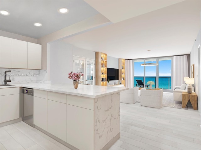 kitchen with pendant lighting, light stone countertops, tasteful backsplash, a water view, and sink