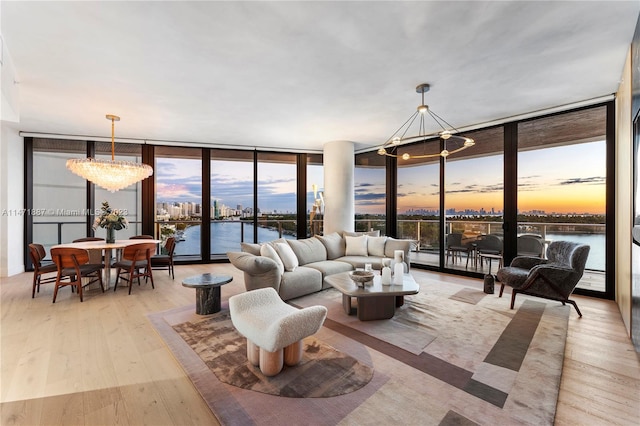 living room with a wall of windows, a chandelier, light wood-type flooring, and a water view