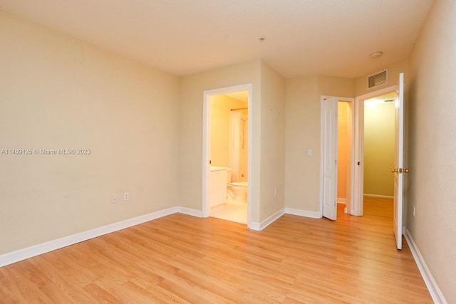 unfurnished bedroom with light hardwood / wood-style flooring and ensuite bath