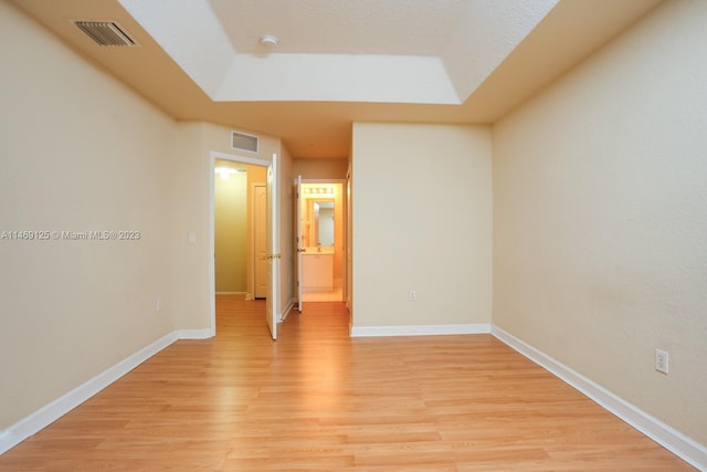 unfurnished bedroom featuring a raised ceiling and light hardwood / wood-style floors