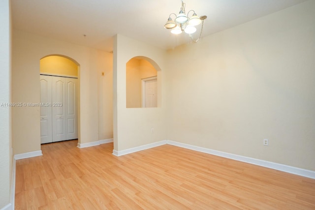 empty room with light hardwood / wood-style floors and a notable chandelier