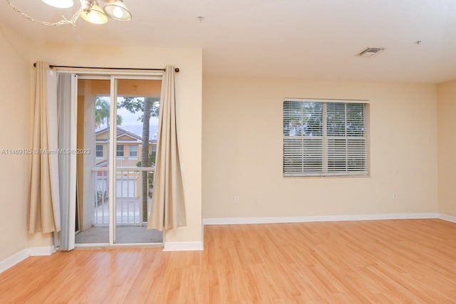 empty room with an inviting chandelier and light hardwood / wood-style floors