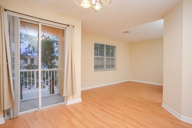 spare room with light hardwood / wood-style floors and a chandelier