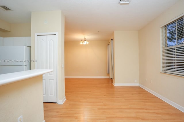 unfurnished room featuring light hardwood / wood-style flooring and a chandelier