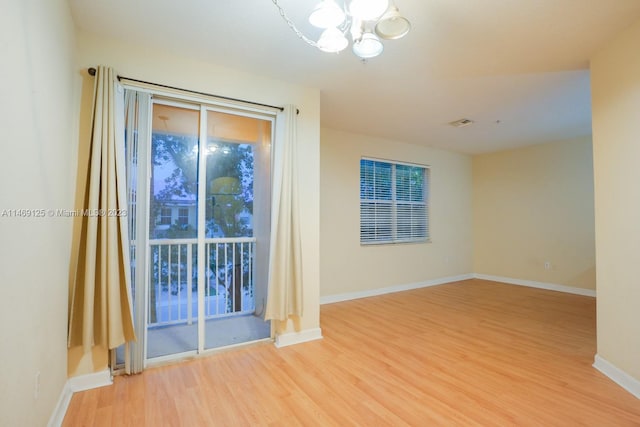 empty room featuring light wood-type flooring and a chandelier