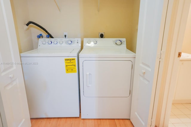 clothes washing area featuring light hardwood / wood-style flooring and washing machine and dryer