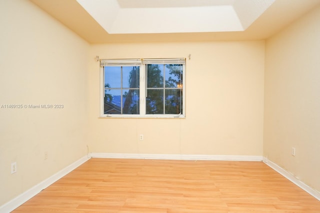 spare room featuring light hardwood / wood-style floors and a tray ceiling