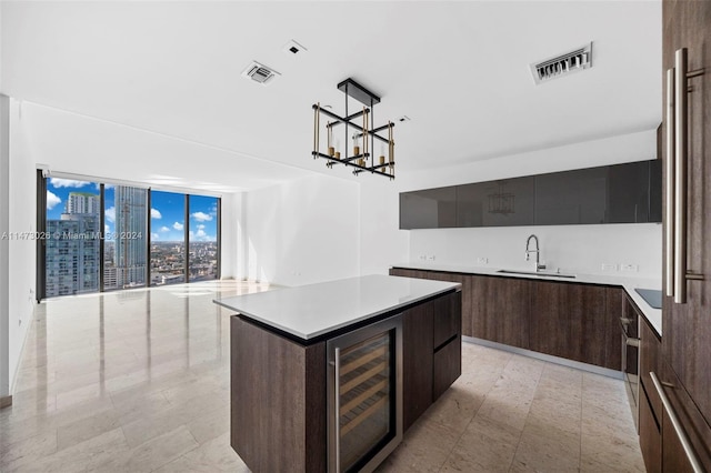 kitchen featuring a chandelier, a kitchen island, decorative light fixtures, beverage cooler, and sink