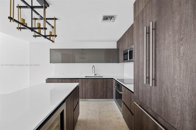 kitchen with dark brown cabinets, appliances with stainless steel finishes, light tile floors, and sink