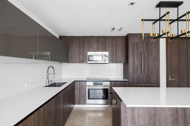 kitchen with sink, light tile floors, a chandelier, stainless steel appliances, and dark brown cabinetry