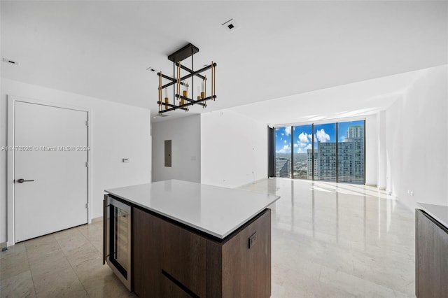 kitchen featuring a wall of windows, light tile floors, wine cooler, a notable chandelier, and a center island