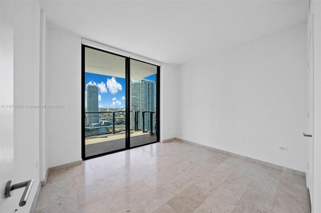 unfurnished room featuring light tile flooring and expansive windows