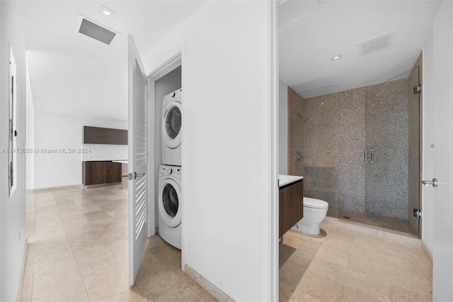laundry area featuring stacked washer / drying machine and light tile floors