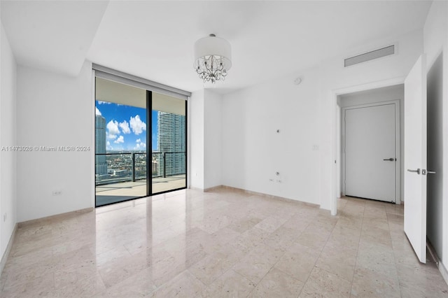 empty room with light tile floors, expansive windows, and a chandelier