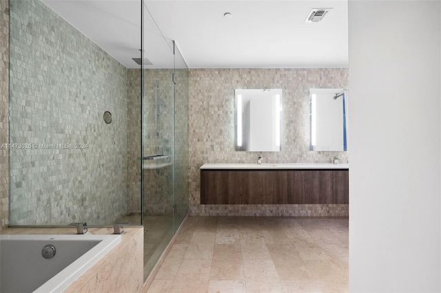 bathroom featuring dual vanity, tile flooring, shower with separate bathtub, and tile walls