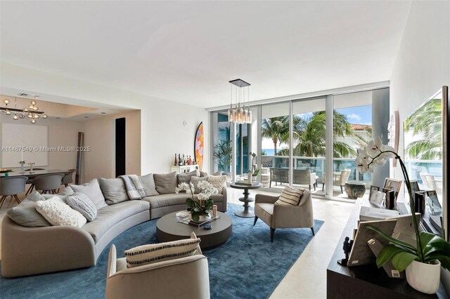 living room featuring plenty of natural light, a chandelier, and a wall of windows